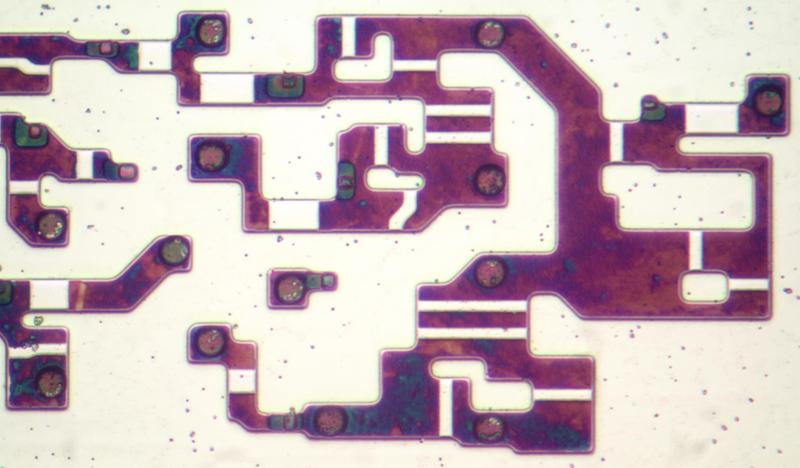 Closeup of some transistors in the 8086. The metal and polysilicon layers have been removed in this photo. The doped silicon has a dark purple appearance due to thin-film interference.