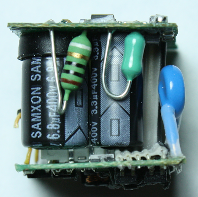 Apple iPhone charger, showing the fusible resistor (striped), inductor (green) and Y capacitor (blue). The two electrolytic filter capacitors are behind (black)