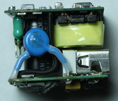 Inside the iPhone charger: input inductor (green), Y capacitor (blue), flyback transformer (yellow), USB connector (silver). The primary circuit board is on top and the secondary board on the bottom.