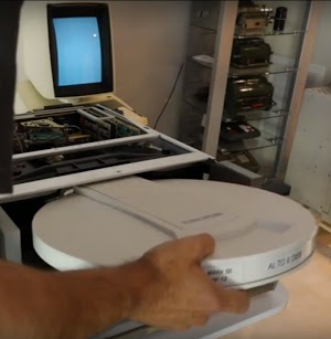 Inserting a disk into the Xerox Alto's disk drive. The Alto's video display is visible at the back.