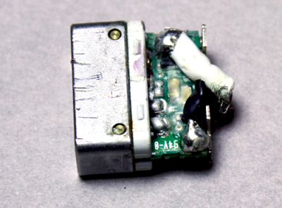 After removing more plastic, the circuit board inside a Magsafe connector is visible. The power cable is soldered onto the board.