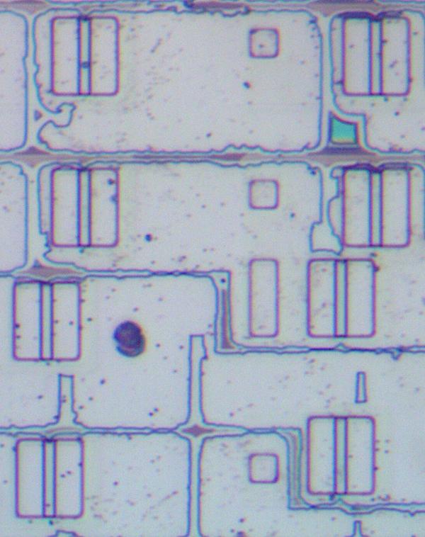 This photo of the underlying silicon shows eight transistors. The top four transistors are shifted one position to the right. the irregular lines are remnants of other layers that I couldn't completely remove from the die.