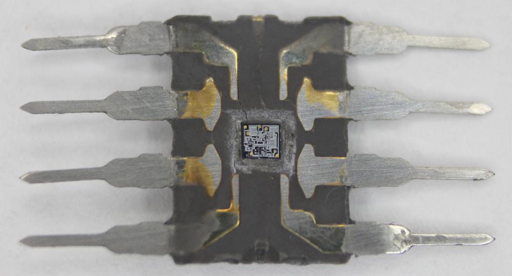 The 555 timer with the package sanded down to expose the silicon die, the tiny square in the middle.