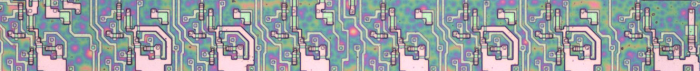 The ACT register in the 8085. This image shows the silicon that implements the 8-bit register. Each of the large pink structures is one bit.  Bit 7 is on the left and bit 0 on the right.