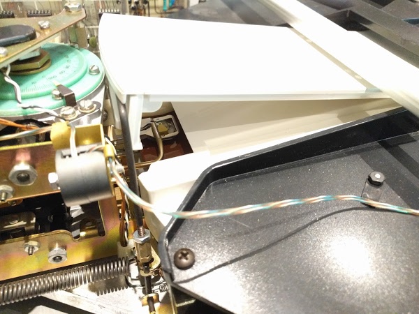 Closeup of the hard disk inside the Diablo drive. The read/write head (metal/yellow) is visible above the disk surface (brown).