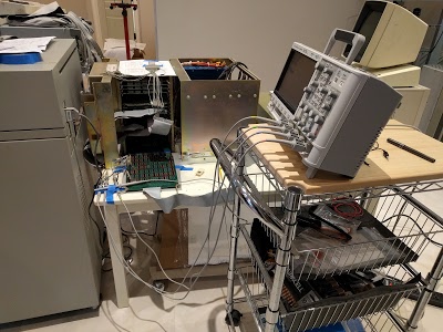 Our test setup for the Xerox Alto. The Alto computer itself is the metal cabinet in the center with the visible circuit boards. On the left is a vintage HP line printer, with the logic analyzer behind it. The video display for the Alto is visible on the right, behind the oscilloscope.