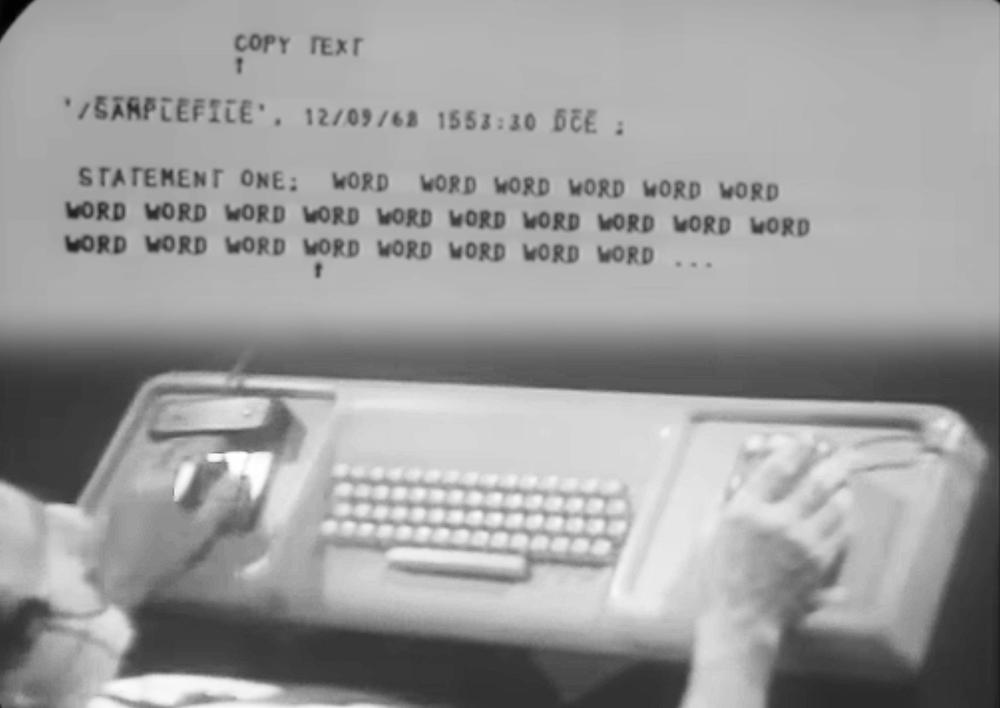 Engelbart using the keyset to edit text. Note that the display doesn't support lowercase text; instead, uppercase is indicated by a line above the character. Adapted from The Mother of All Demos.