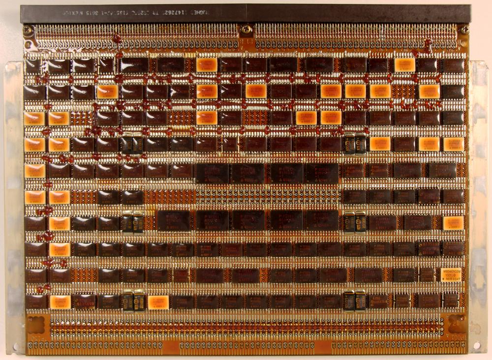 One of the CPU boards from the AP-101S, specifically the CPU1 board. If you look closely, you can see "bodge wires" that correct errors on the board. The nine large ICs in the center are four-bit arithmetic-logic unit chips (74F181) for the 36-bit "fraction" ALU. Much of the logic uses FAST (Fairchild Advanced Schottky Technology) TTL chips for improved performance. The board is covered with brown conformal coating to protect it from the environment. Click this image (or any other) for a larger version.
