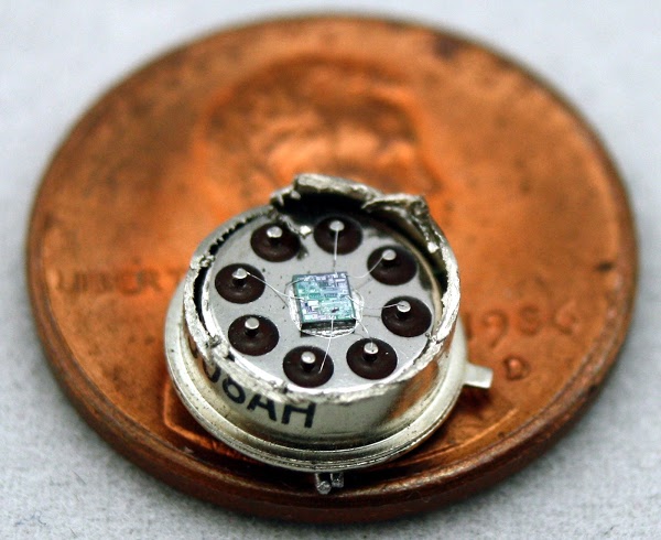 The LM308 op amp has been cut open revealing the tiny die inside. Pads on the die are connected to the pins with thin bond wires.