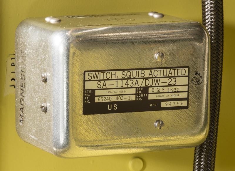 The squib-activated switch, next to a coolant line.
The manufacturer of this part is Boeing, as indicated by the Cage Code 94756 on the part.
Image from National Air and Space Museum.