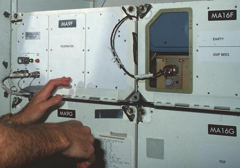 The teleprinter in middeck locker MA9F on flight STS-41C.  The hands belong to mission specialist van Hoften.  From National Archives; the description says the photo is from 1995 and shows the Thermal Impulse Printer system, but both are wrong. (STS-41C was in April, 1984.)