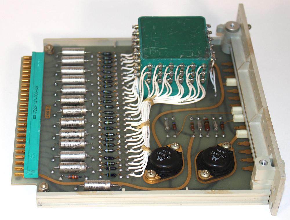 The switching power supply board is dominated by a large green transformer with many windings. The two black power transistors are at the front.